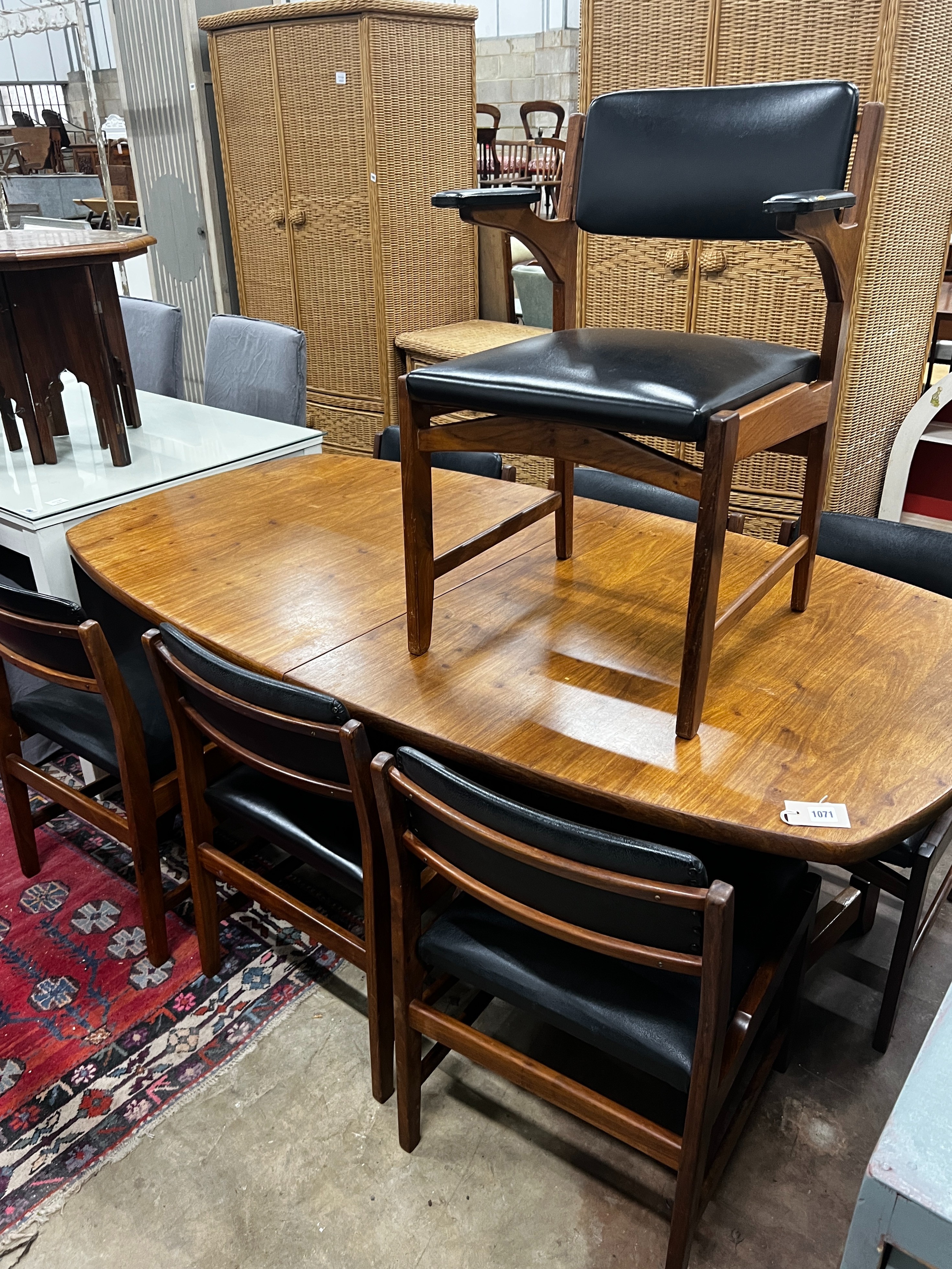 A mid century Novocraft teak dining suite comprising extending dining table 230cm extended, width 97cm, height 74cm, seven black leatherette chairs, one with arms and a sideboard width 178cm.